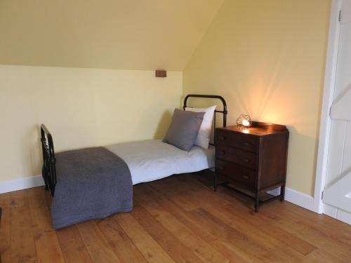 - une chambre avec un lit et une commode avec une lampe dans l'établissement La Boucharderie, à Val Couesnon