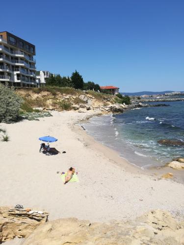 two people on a beach with an umbrella at Hotel Diva in Ravda