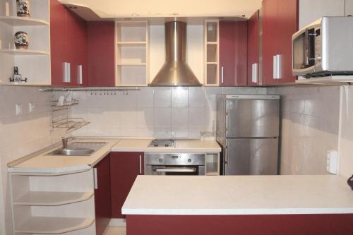 eine Küche mit roten Schränken und einem Kühlschrank aus Edelstahl in der Unterkunft Las Palmas in Pomorie
