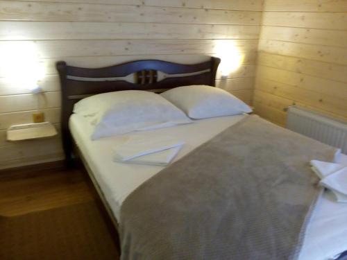 a bedroom with a bed with white sheets and pillows at Садиба у Брусків in Mizhhirʼʼya