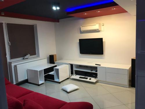 a living room with a red couch and a flat screen tv at Korona Panzió in Balog nad Ipľom