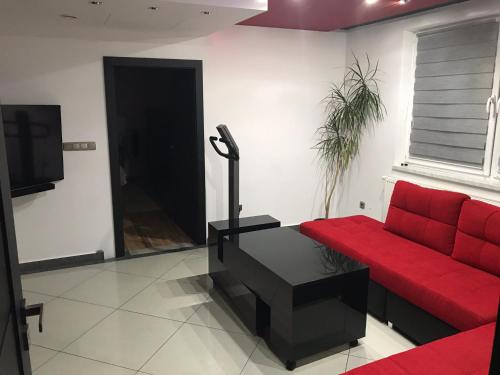 a living room with a red couch and a tv at Korona Panzió in Balog nad Ipľom