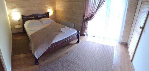 a bedroom with a bed and a large window at Садиба у Брусків in Mizhhirʼʼya