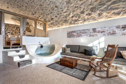 a bathroom with a tub and a couch and a chair at Canava Villas in Santorini in Emporio Santorini