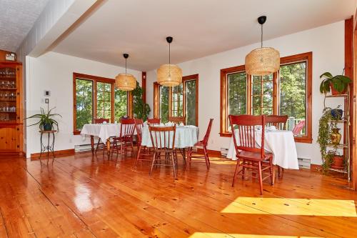 a dining room with tables and chairs and windows at Auberge de la Tour et Spa in Magog-Orford