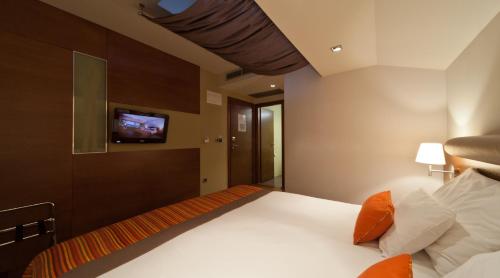 a bedroom with a bed with a tv on the wall at Hotel Kaj in Marija Bistrica
