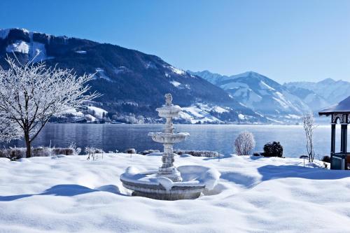 a fountain in the snow in front of a lake at Grand Hotel Zell am See in Zell am See
