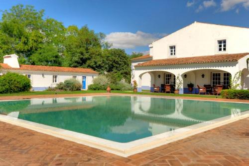 a swimming pool in front of a house at Hotel Rural Monte Da Rosada in Estremoz