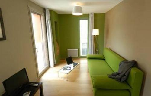 ein Wohnzimmer mit einem grünen Sofa und einem Tisch in der Unterkunft Temporesidence Cathedrale in Bayonne