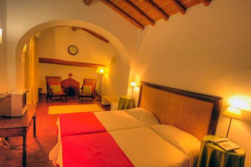 a bedroom with a bed and a table and a television at Hotel Rural Monte Da Rosada in Estremoz