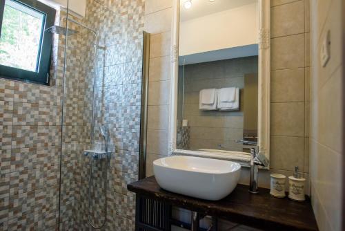 ein Bad mit einem Waschbecken und einer Glasdusche in der Unterkunft Belleview Suites in Mamaia
