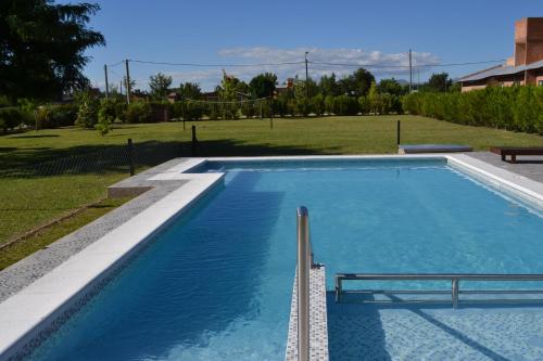 a large swimming pool with blue water in a yard at Aguas Mornas Cabañas in Mina Clavero