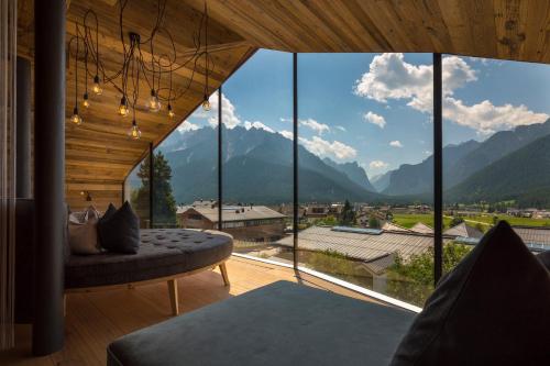 a room with a large window with a view of mountains at Hotel Villa Monica in Dobbiaco