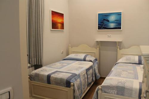 two beds in a small room with paintings on the wall at Nunzia Sweet Home in Naples