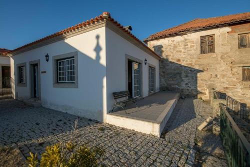 a white building with a bench on the side of it at Quinta Sta Luzia Carrascal in Vila Flor