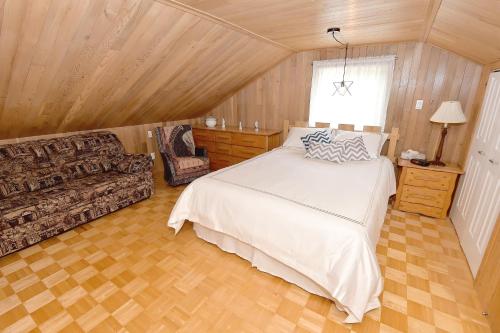 een slaapkamer met een bed en een bank in een kamer bij Paradis du Lac Nairne in Notre-Dame-des-Monts