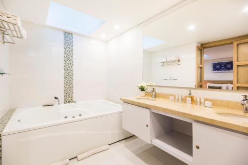 a bathroom with a tub and a sink and a large mirror at Hotel Camino de la Sal in Zipaquirá