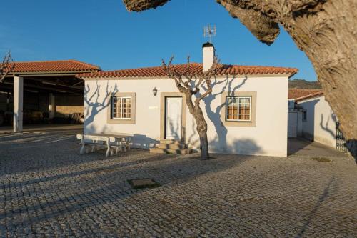 a white building with a tree in front of it at Quinta Sta Luzia Carrascal in Vila Flor