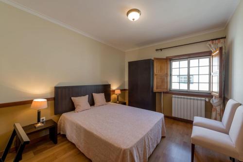 a bedroom with a bed and a chair and a window at Quinta Sta Luzia Carrascal in Vila Flor