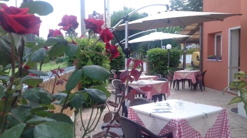 un patio al aire libre con mesas y sillas con rosas rojas en La Campagnola Trattoria con Alloggio en Misano Adriatico