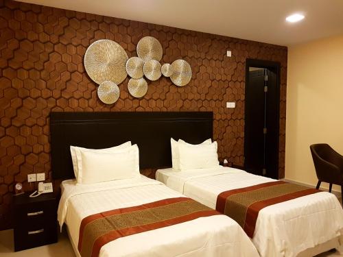 Tanuf Residency Hotel في نزوى‎: سريرين في غرفة فندق مع سريرين sidx sidx