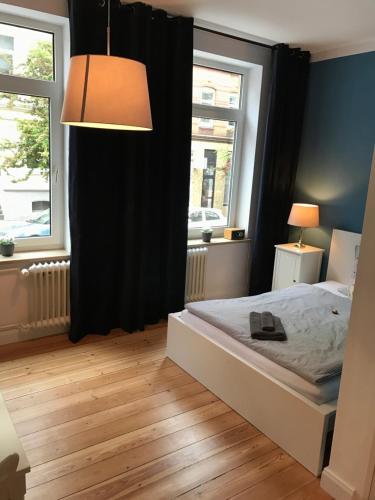 a bedroom with a bed and a lamp and two windows at Nord Apartment in Kiel