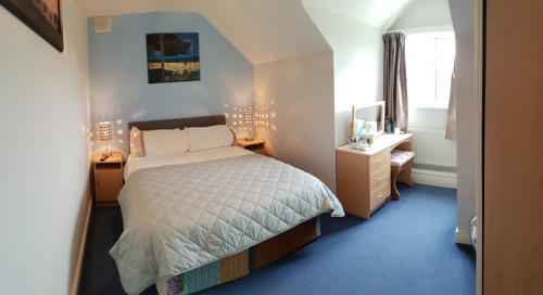 a bedroom with a bed and a desk and a window at Deerpark B&B in Portumna