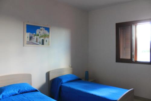 a bedroom with two beds with blue sheets and a window at Residenza Santoro in Melendugno