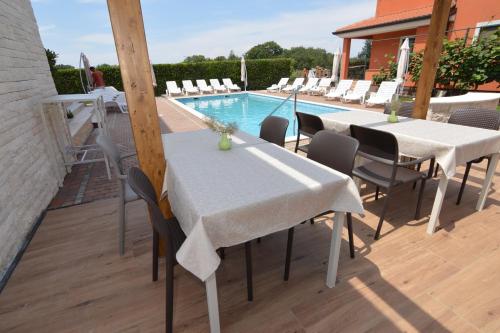 a patio with tables and chairs next to a swimming pool at Hotel Natura Vilanija in Umag