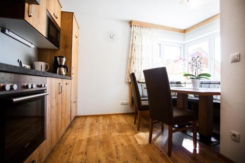 eine Küche mit einem Tisch und Stühlen sowie einem Fenster in der Unterkunft Apartment Aster in Wagrain