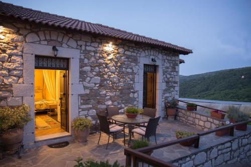 a stone house with a table and chairs on a patio at Tholos in Áno Dholianá