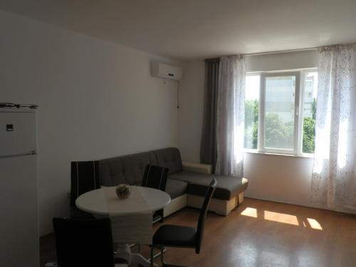 een woonkamer met een bank, een tafel en een raam bij Cocoa Apartment in Varna