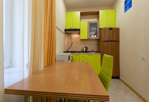 a kitchen with a wooden table and green cabinets at Odnokomnatnaya studiya in Kyiv