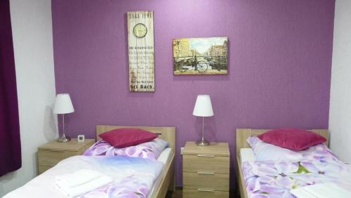 2 Betten in einem Zimmer mit lila Wänden in der Unterkunft Hotel Rodizio UG in Wolfsburg