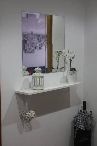 ein weißes Regal mit einem Spiegel und Blumen darauf in der Unterkunft Casa Gonzalez in Posada