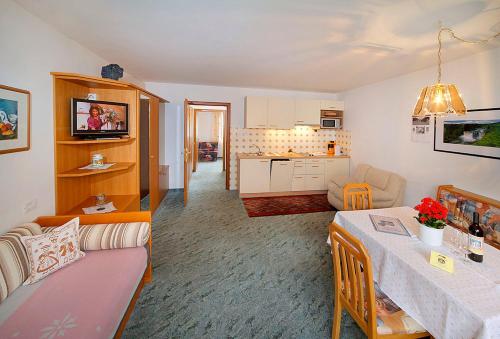 a living room with a table and a kitchen at Pension Villa Claudia Augusta in Resia