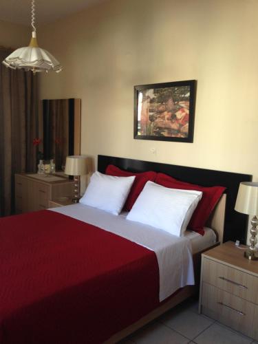 a bedroom with a bed with red sheets and white pillows at Palmira Apartments in Makry Gialos
