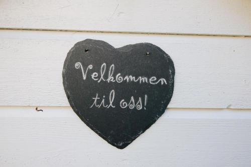 a black and white sign on a wooden post at Gjerdset Turistsenter in Isfjorden