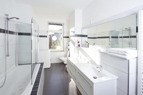 a white bathroom with two sinks and a shower at Apartments-Leipzig in Leipzig
