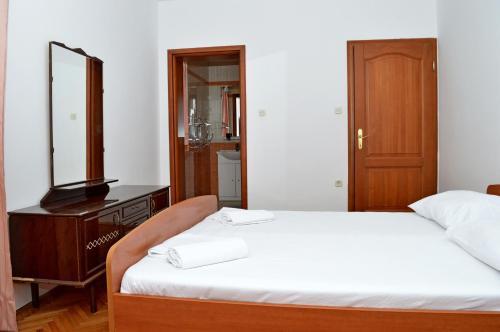 a bedroom with two beds with a mirror and a dresser at Apartments Mačak in Novalja