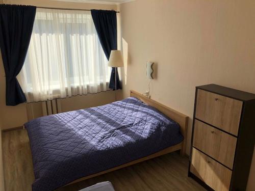 a bedroom with a bed and a dresser and a window at Las Palomas in Ventspils