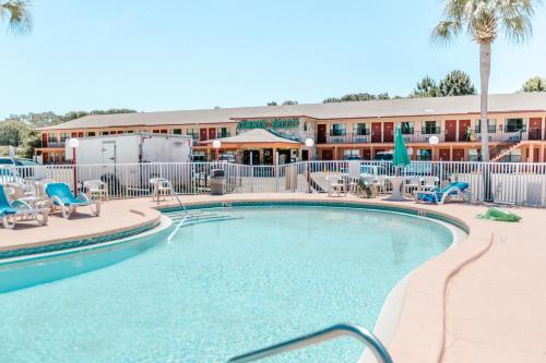 パナマ・シティ・ビーチにあるSummer Breeze Motelの背景にホテルがあり、椅子付きのスイミングプールを併設しています。