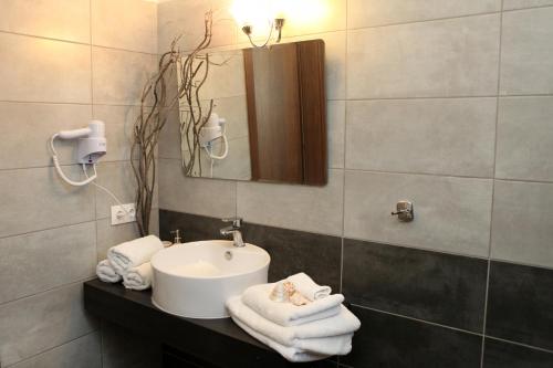 een badkamer met een wastafel, een spiegel en handdoeken bij Iris 2 in Paralia Katerinis