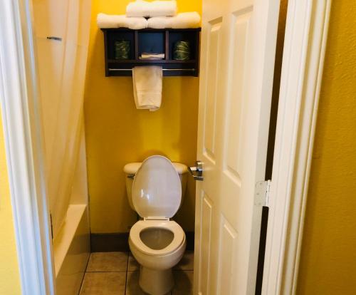 a bathroom with a toilet and towels on a shelf at Days Inn by Wyndham Port Aransas TX in Port Aransas
