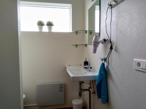 a bathroom with a sink and a mirror and a window at Glæsibær 2 Guesthouse and horsefarm in Akureyri