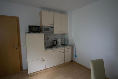 una pequeña cocina con armarios blancos y microondas en Ferienwohnung Ofer Thomas & Michaela, en Neustift im Stubaital