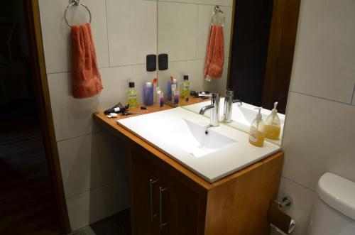 y baño con lavabo blanco y espejo. en Outrippers Pucón en Villarrica