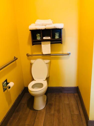 a bathroom with a toilet with yellow walls at Days Inn by Wyndham Port Aransas TX in Port Aransas