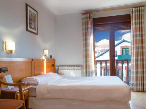 a hotel room with two beds and a window at Hostal La Maya in Cercedilla