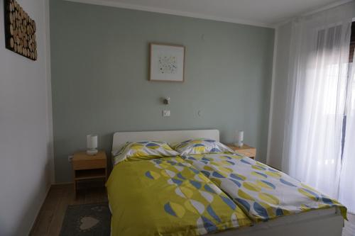 a bed with a yellow and blue comforter in a bedroom at Apartma Irena Volče in Volzana